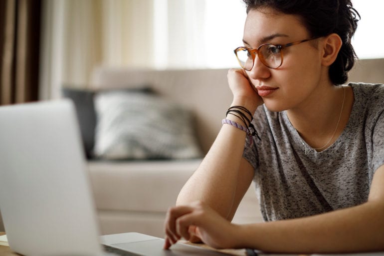 woman with glasses typing on computer