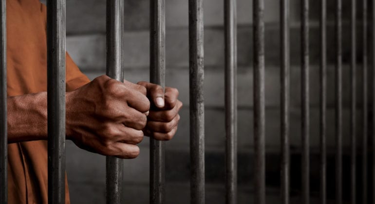hands holding prison bars