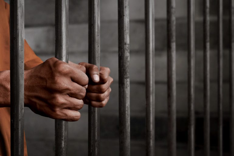 hands holding prison bars