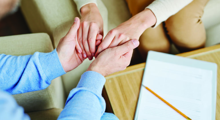 people holding hands with paper and pencil in the background