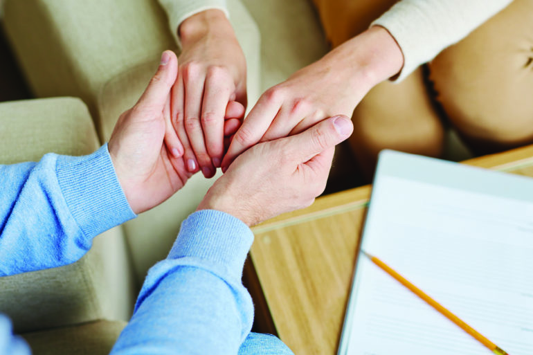 people holding hands with paper and pencil in the background