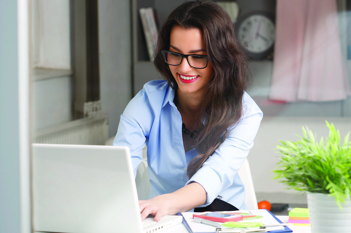 woman with glasses and red lipstick smiling while typing