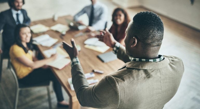 man speaking to group of coworkers