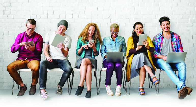people sitting on chair looking at phones and tablets