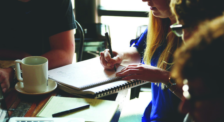 woman writing notes in spiral notebook