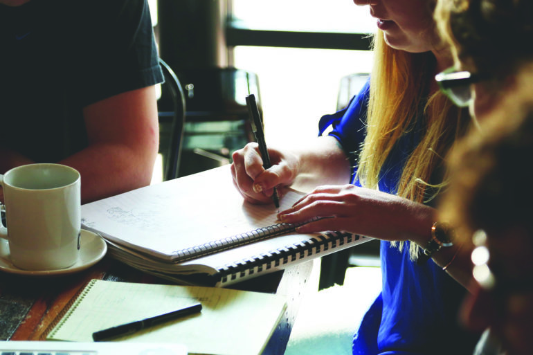 woman writing notes in spiral notebook