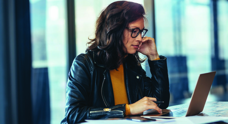 woman in glasses looking at a computer
