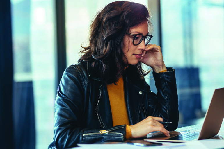 woman in glasses looking at a computer
