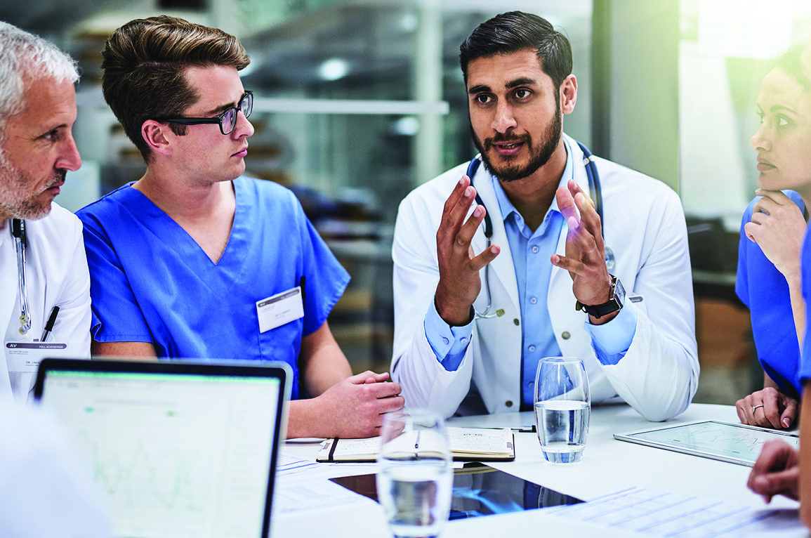 male doctor talking to team of nurses and doctors