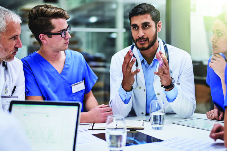 male doctor talking to team of nurses and doctors