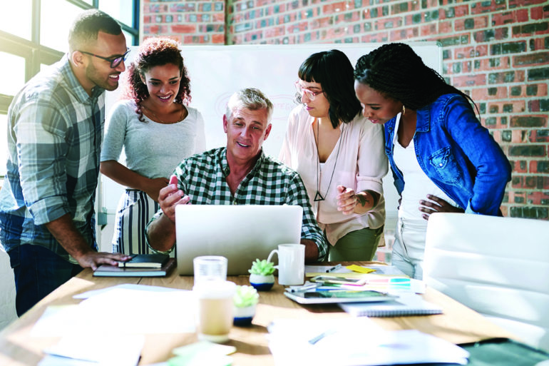 team of people working around one laptop