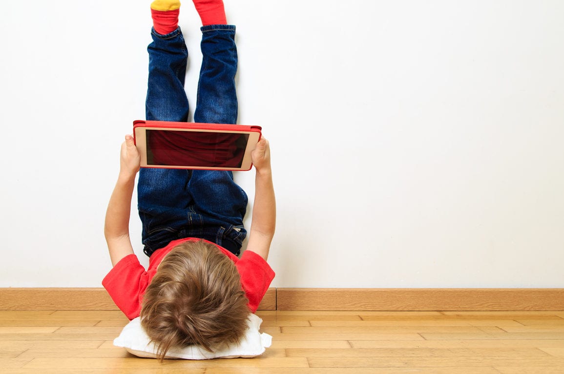 child with tablet reading upside down