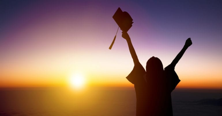 a graduate looking at a sunrise
