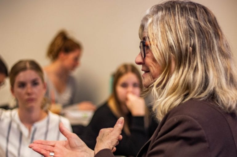 woman talking in front of group of young women