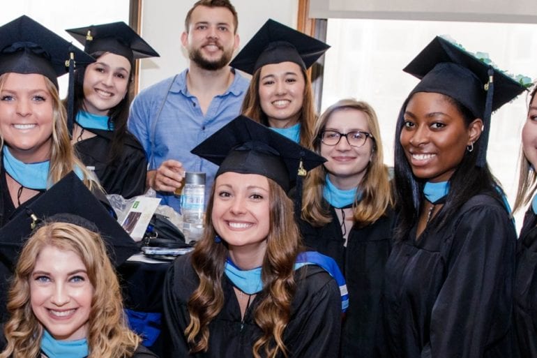group of college graduates with light blue scarves
