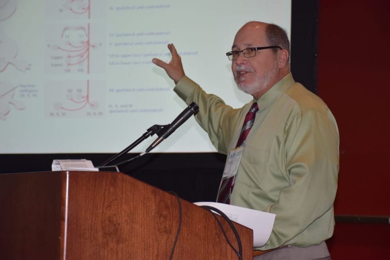 man in a greenish yellow shirt giving a presentation at a podium