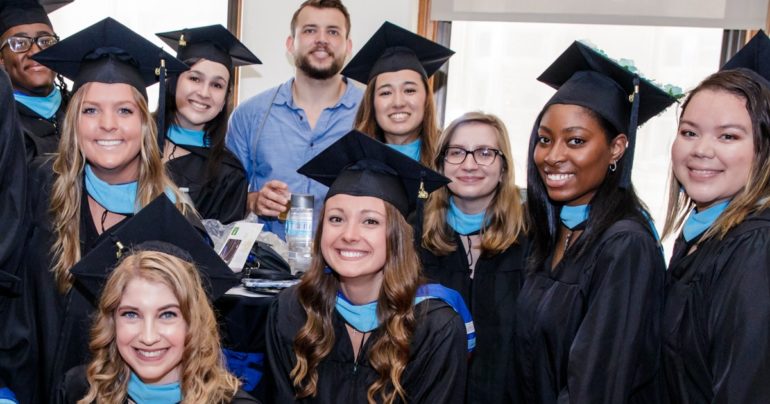 many students in caps and gowns with blue neck scarves