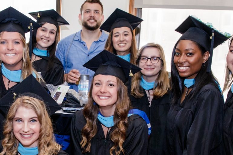 many students in caps and gowns with blue neck scarves