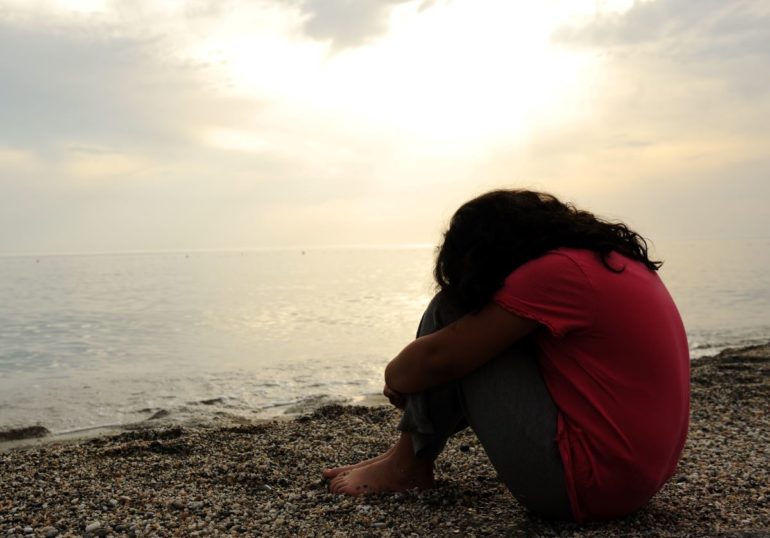 woman with head on needs by water