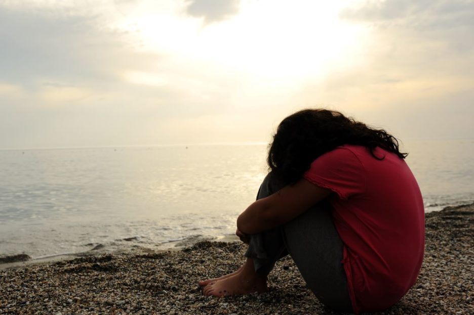woman with head on needs by water
