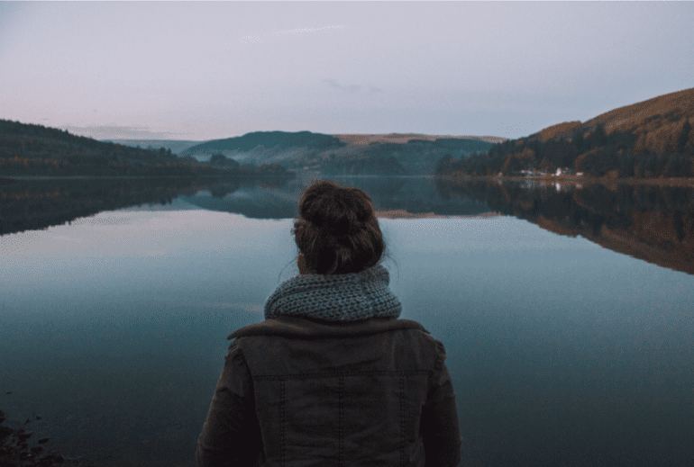woman looking out at lake and hill scenery