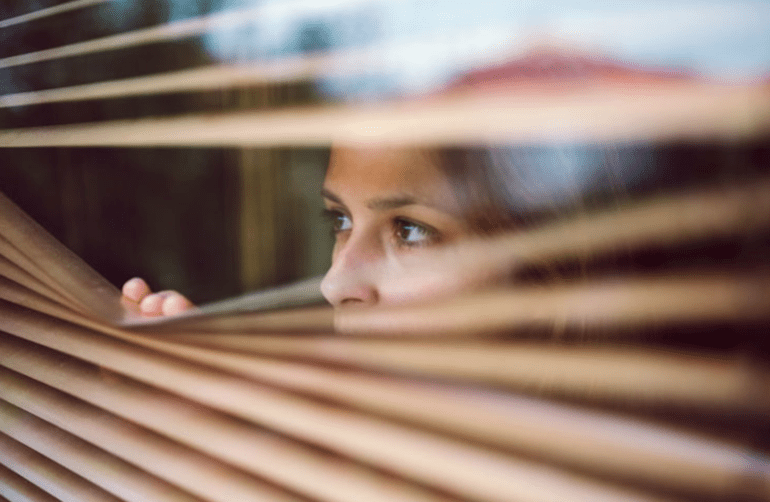 woman peeking through blinds