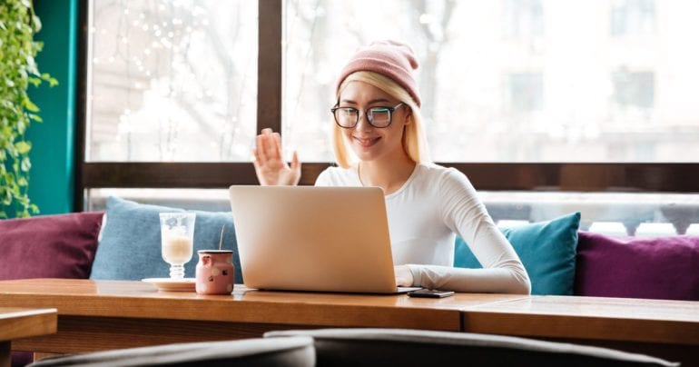 woman in pink hat waving to laptop