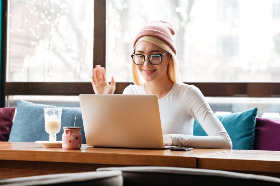 woman in pink hat waving to laptop