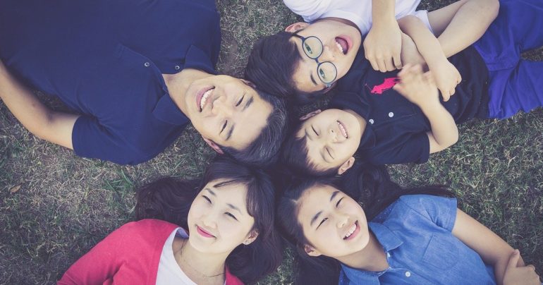 family of five with there heads together laying on the grass