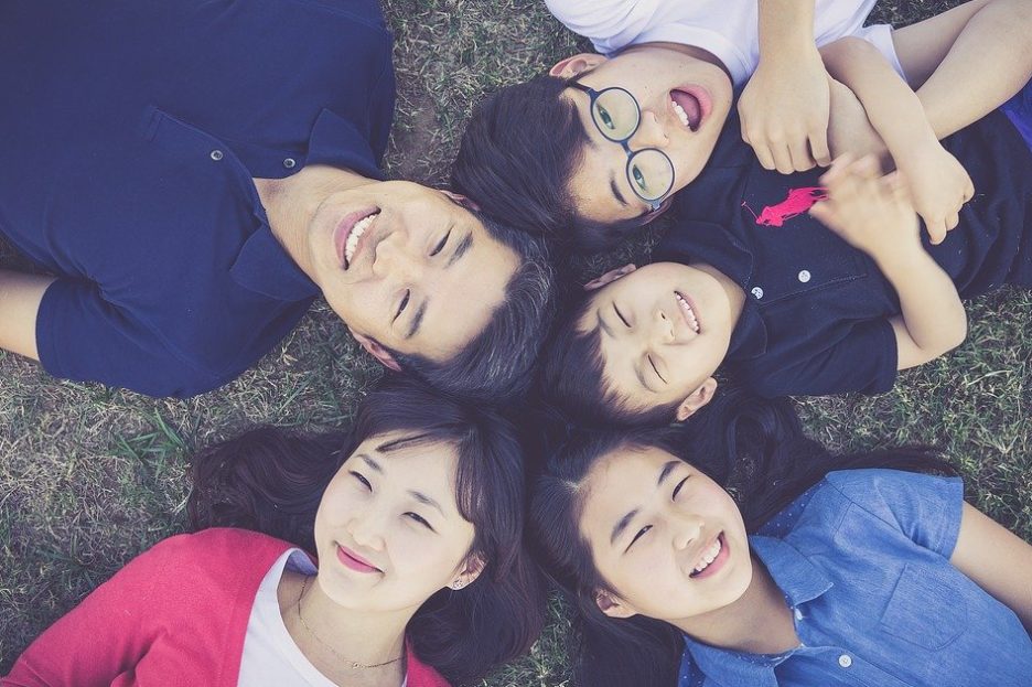 family of five with there heads together laying on the grass