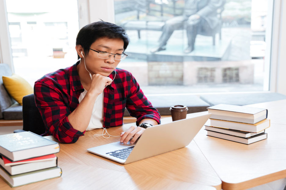 man in black and red flannel looking at laptop