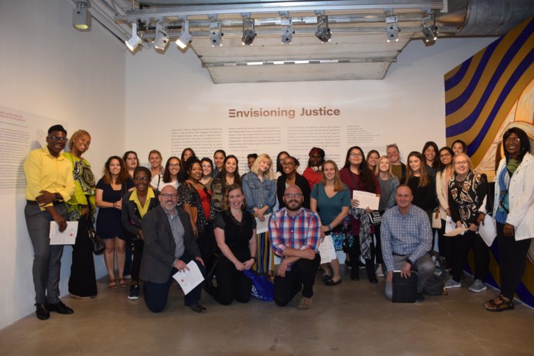 large group of people posing for photo with Envisioning Justice on the wall