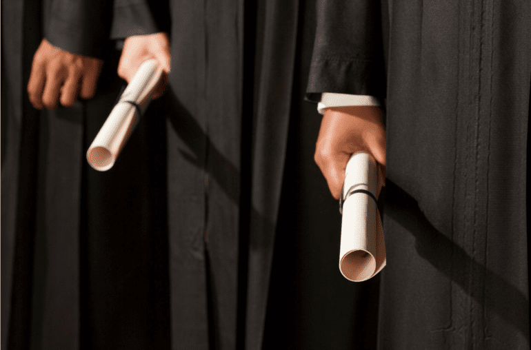 close up of grads holding rolled up diplomas