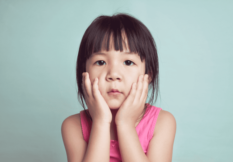 young girl with hands on her cheeks