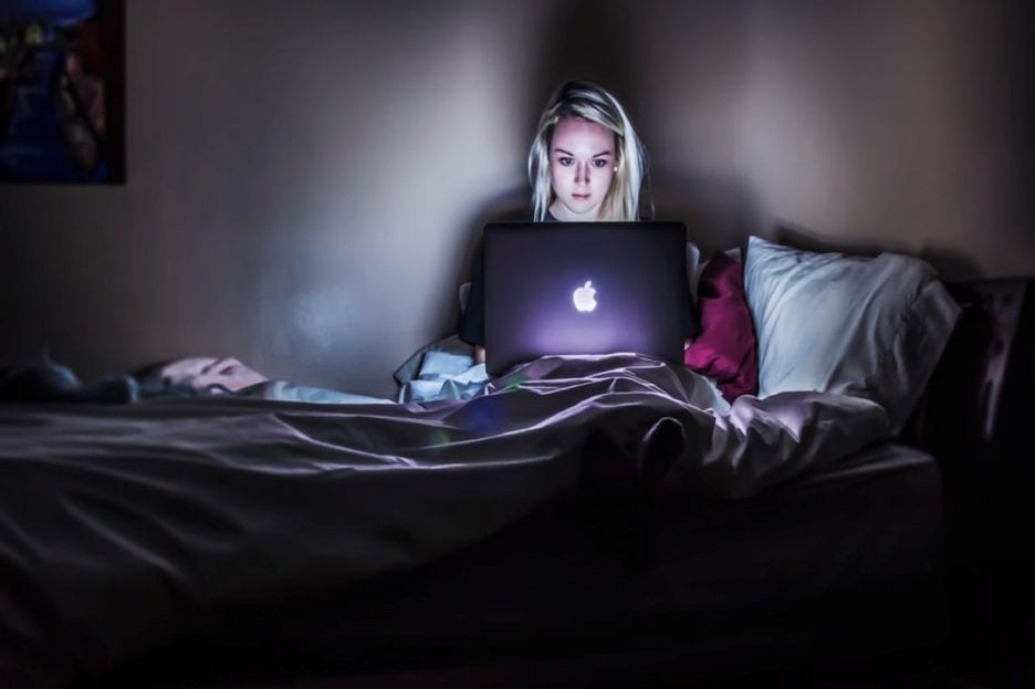 woman in bedroom with the glow of a laptop on her