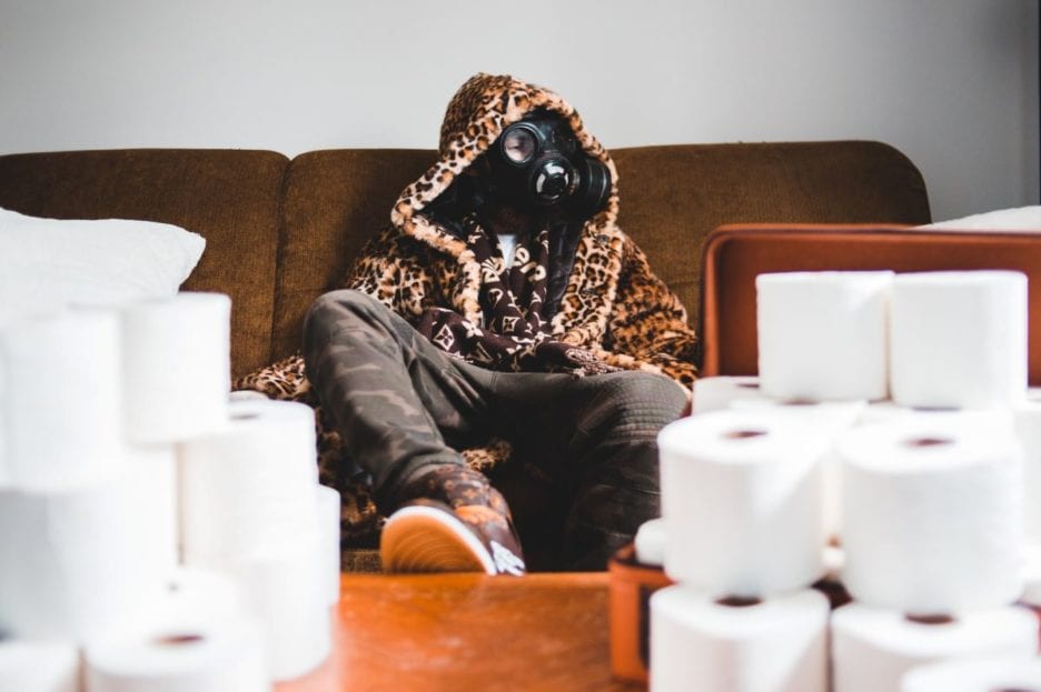 man wearing gas mask hoarding toilet paper in his house