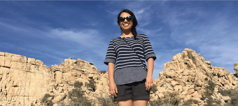 woman standing against blue sky and rocks