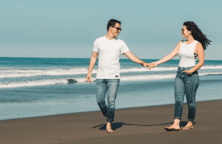 couple holding hands while walking on the beach
