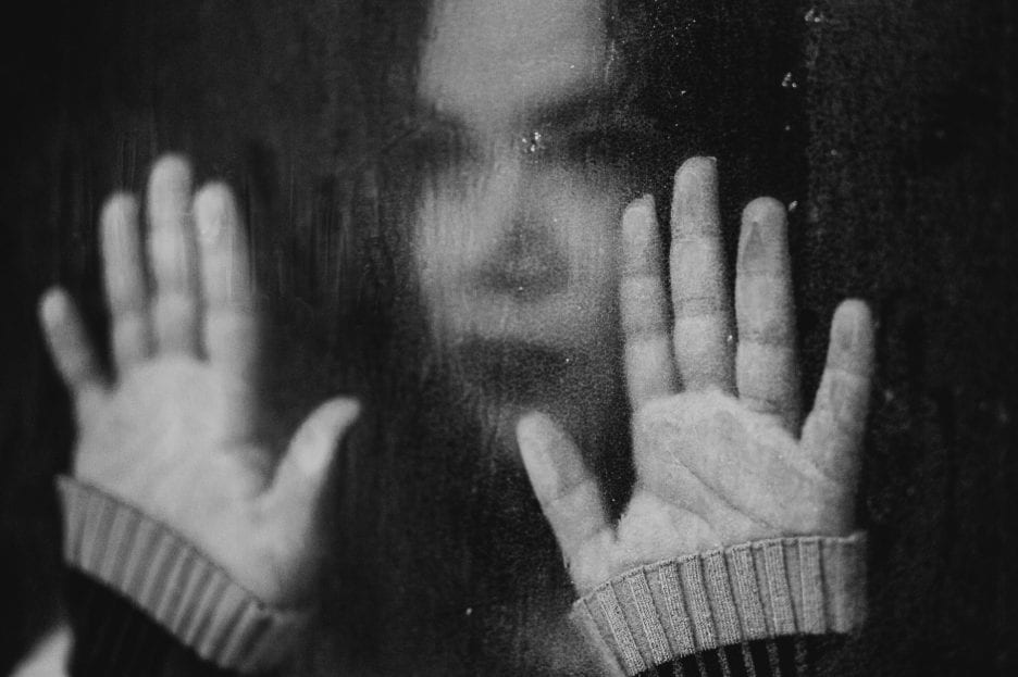 black and white photo of woman with hands on glass