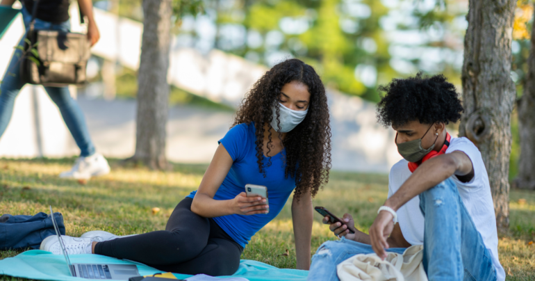 students on their cell phones in a park