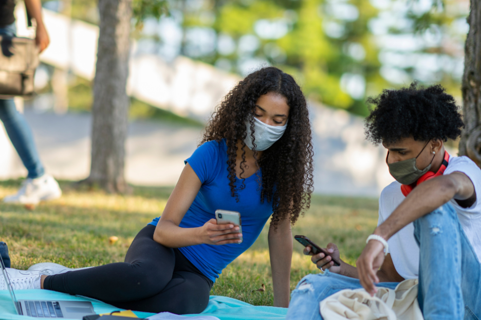 students on their cell phones in a park
