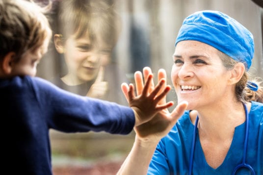 nurse looking at child through glass window