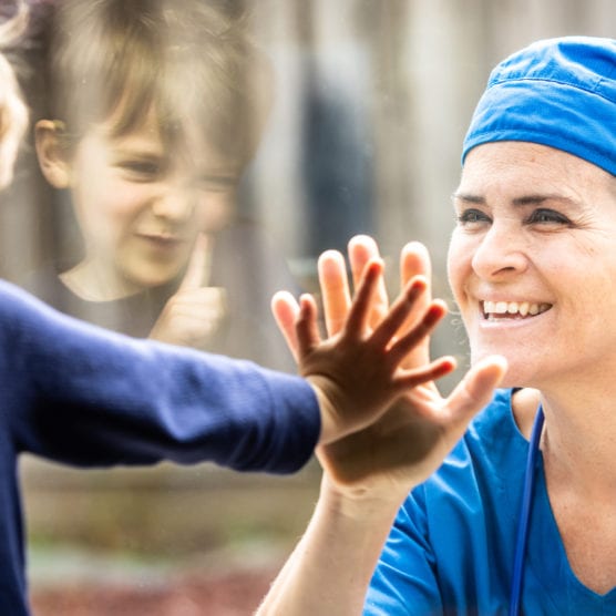 nurse looking at child through glass window