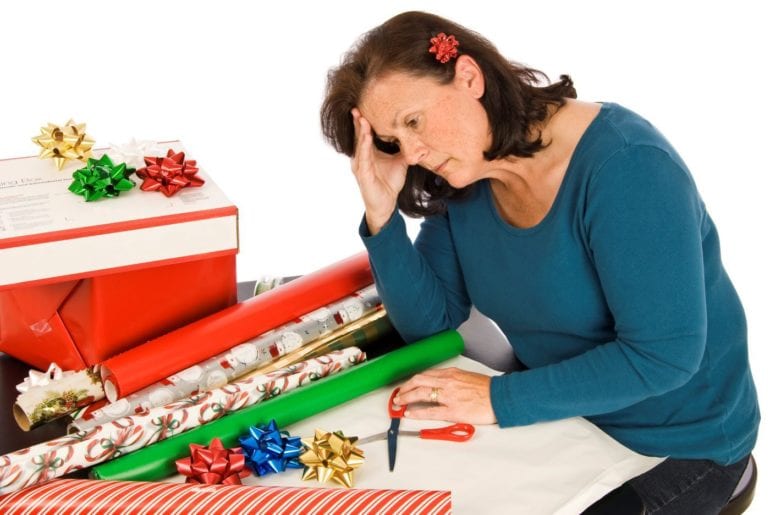 woman looking stressed at table with gift wrapping materials