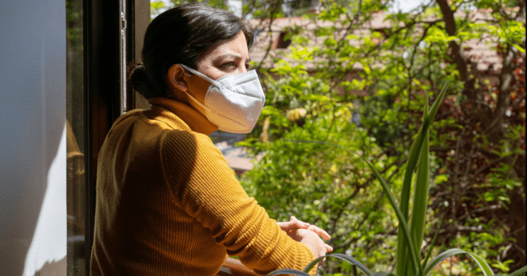 woman wearing a mask looking outside
