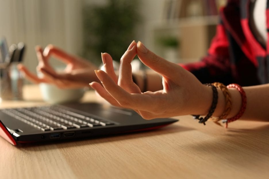 student meditating at laptop