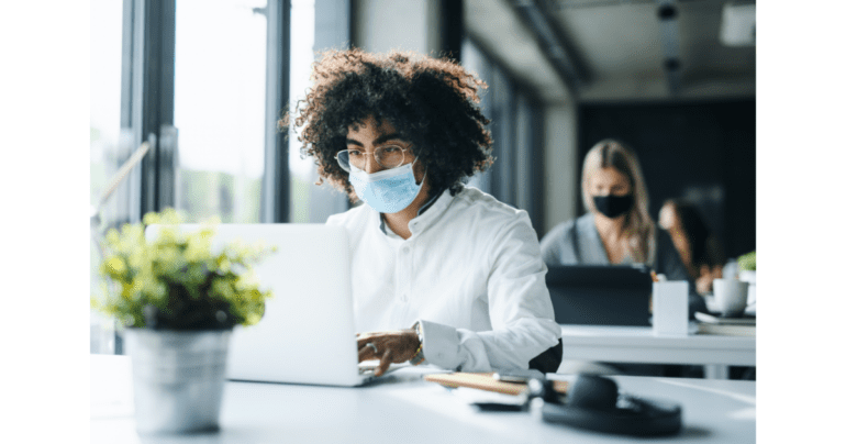 Person sitting at laptop with mask on