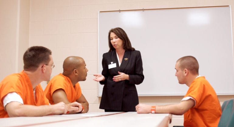 inmates in orange suits meeting with counselor