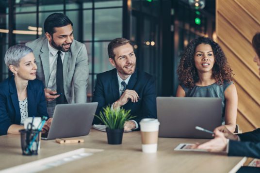 group of men and women gathered around a table in office setting