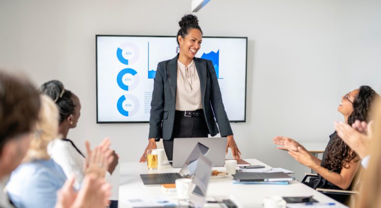 woman standing at head of table and presenting